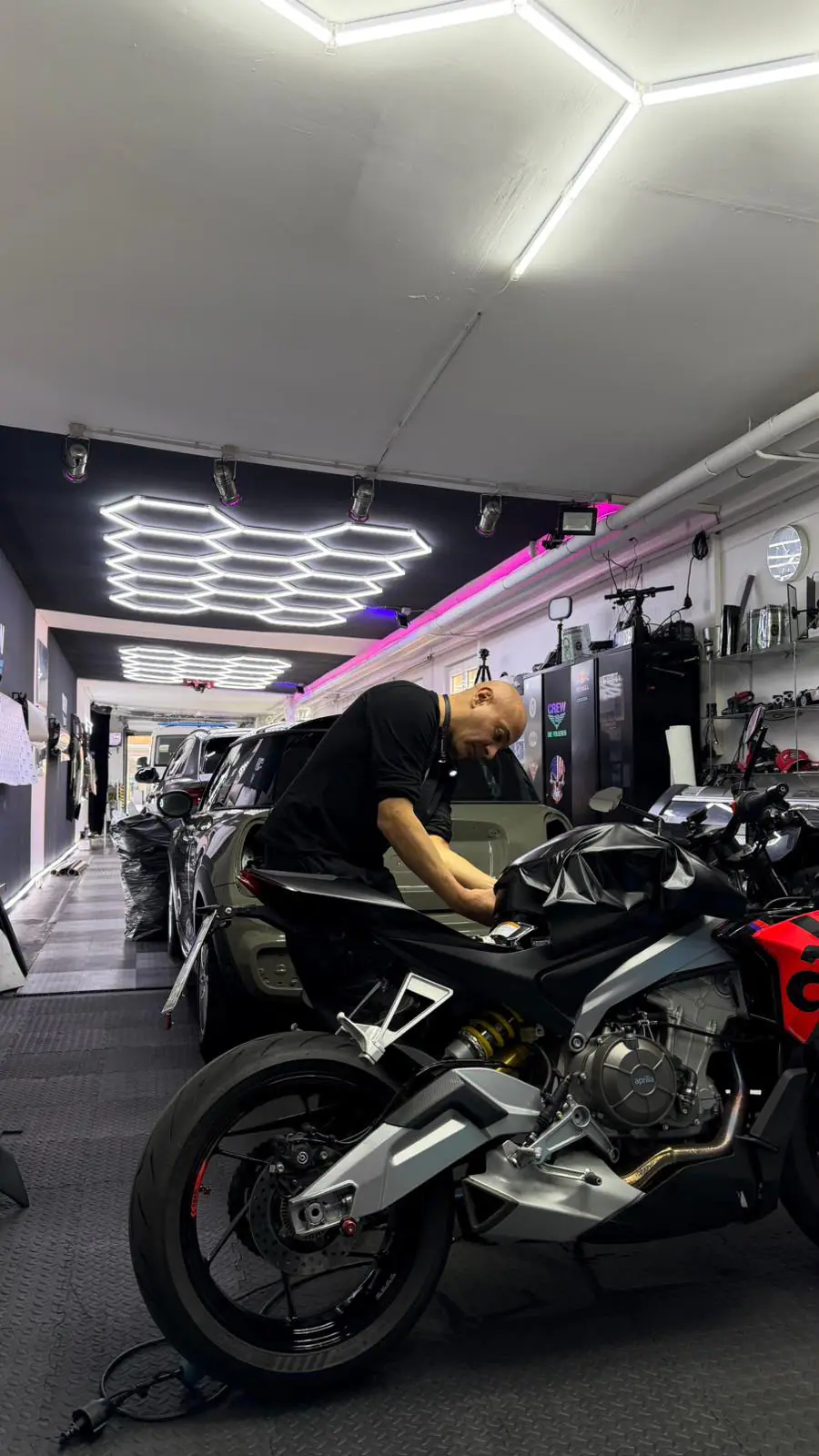 Folierer arbeitet an einem Motorrad in der Werkstatt mit Wabenlicht