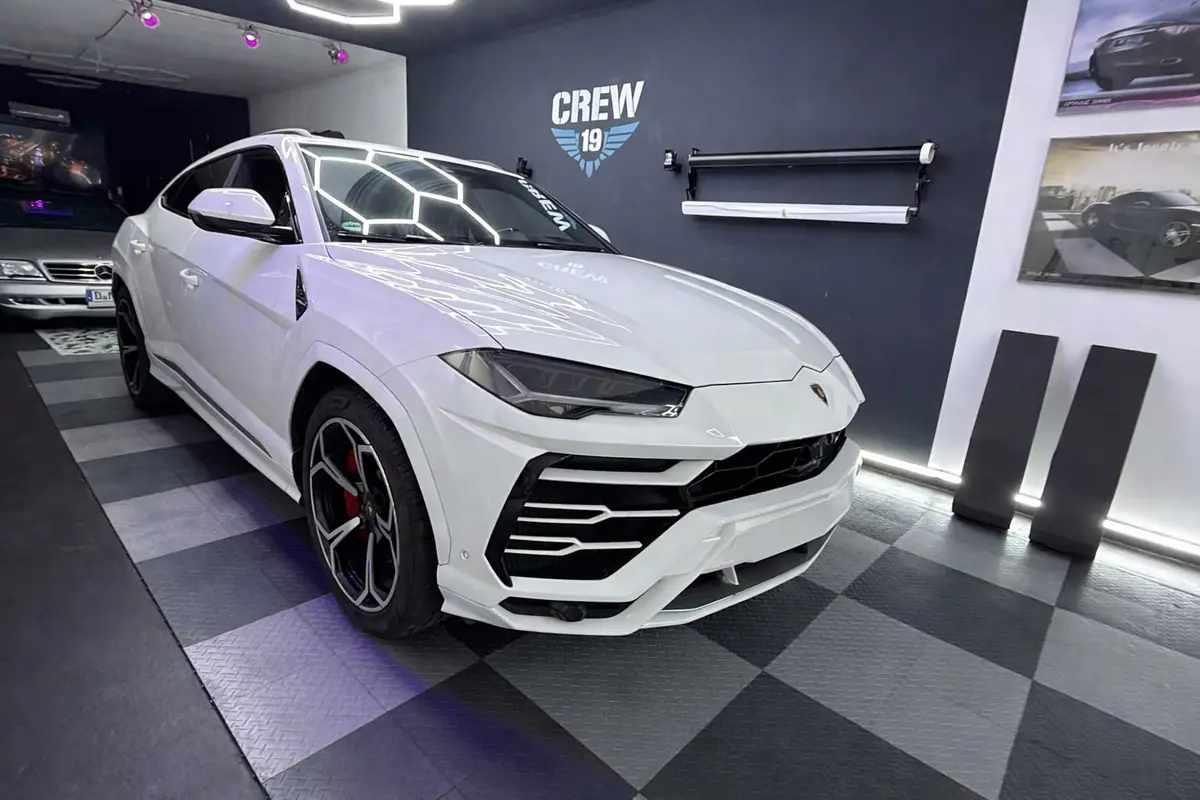 Weißer Lamborghini Urus vor der CREW-19-Wand