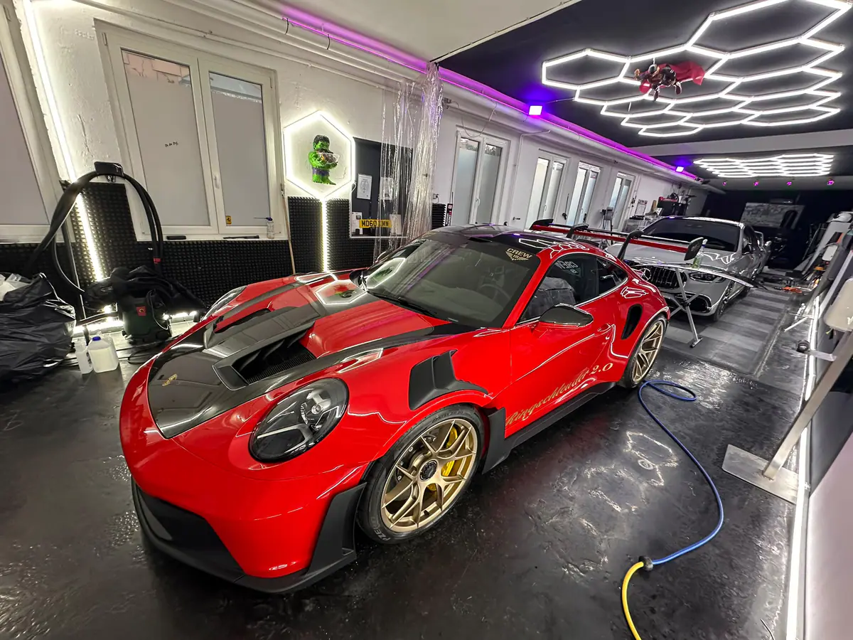 Roter Porsche 911 GT3 RS mit schwarzer Haube auf dem Werkstattboden